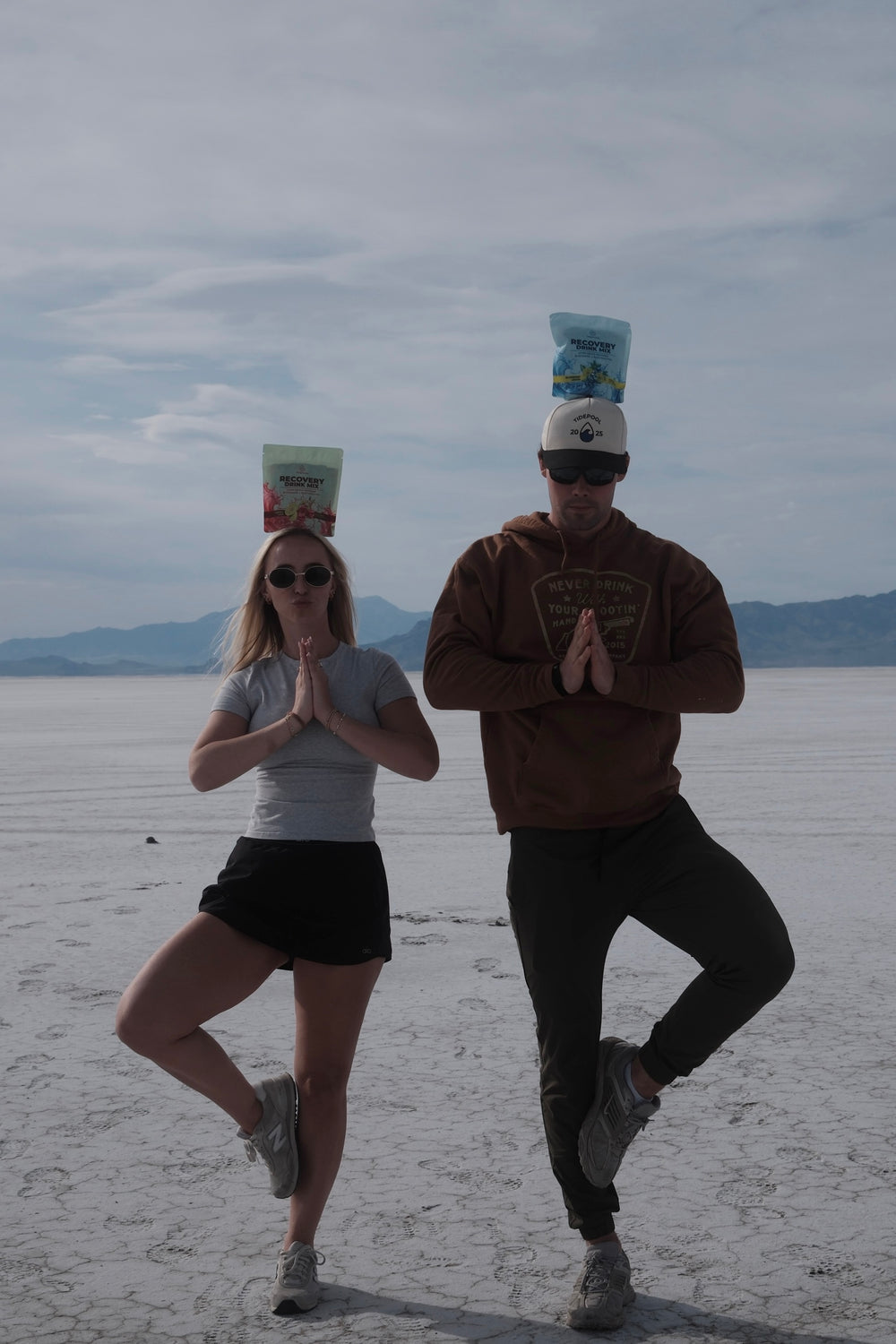 Two people with buckets on their heads in a desert landscape