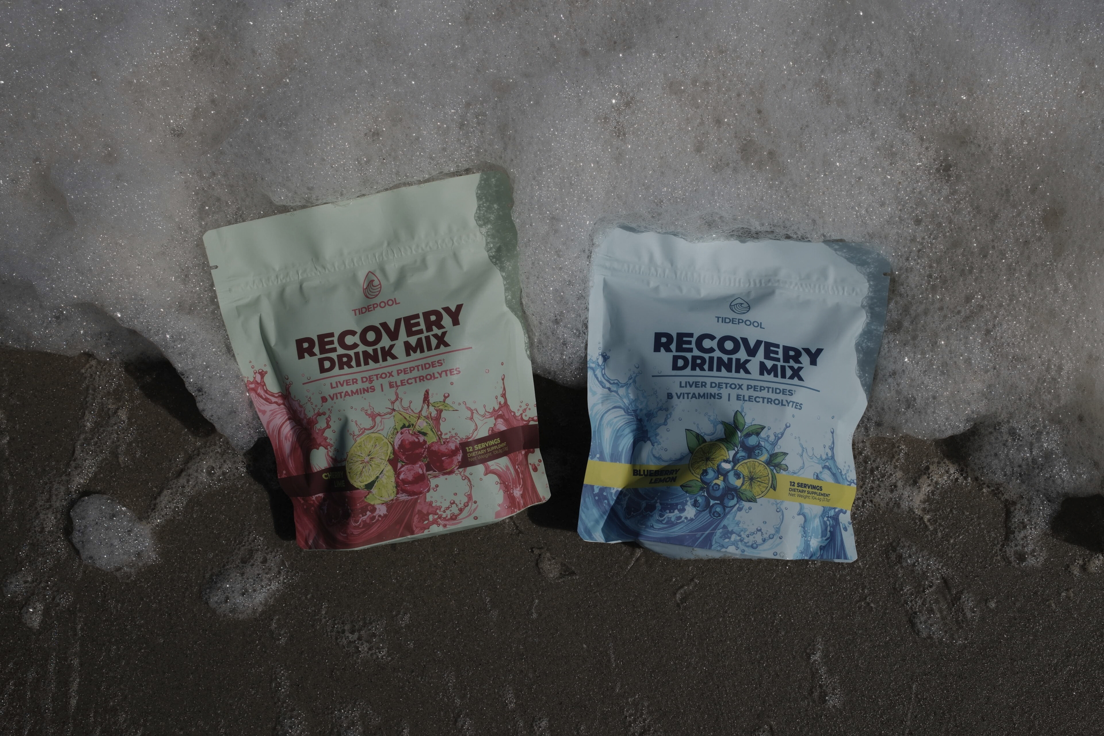Two packages of recovery drink mix on a concrete surface
