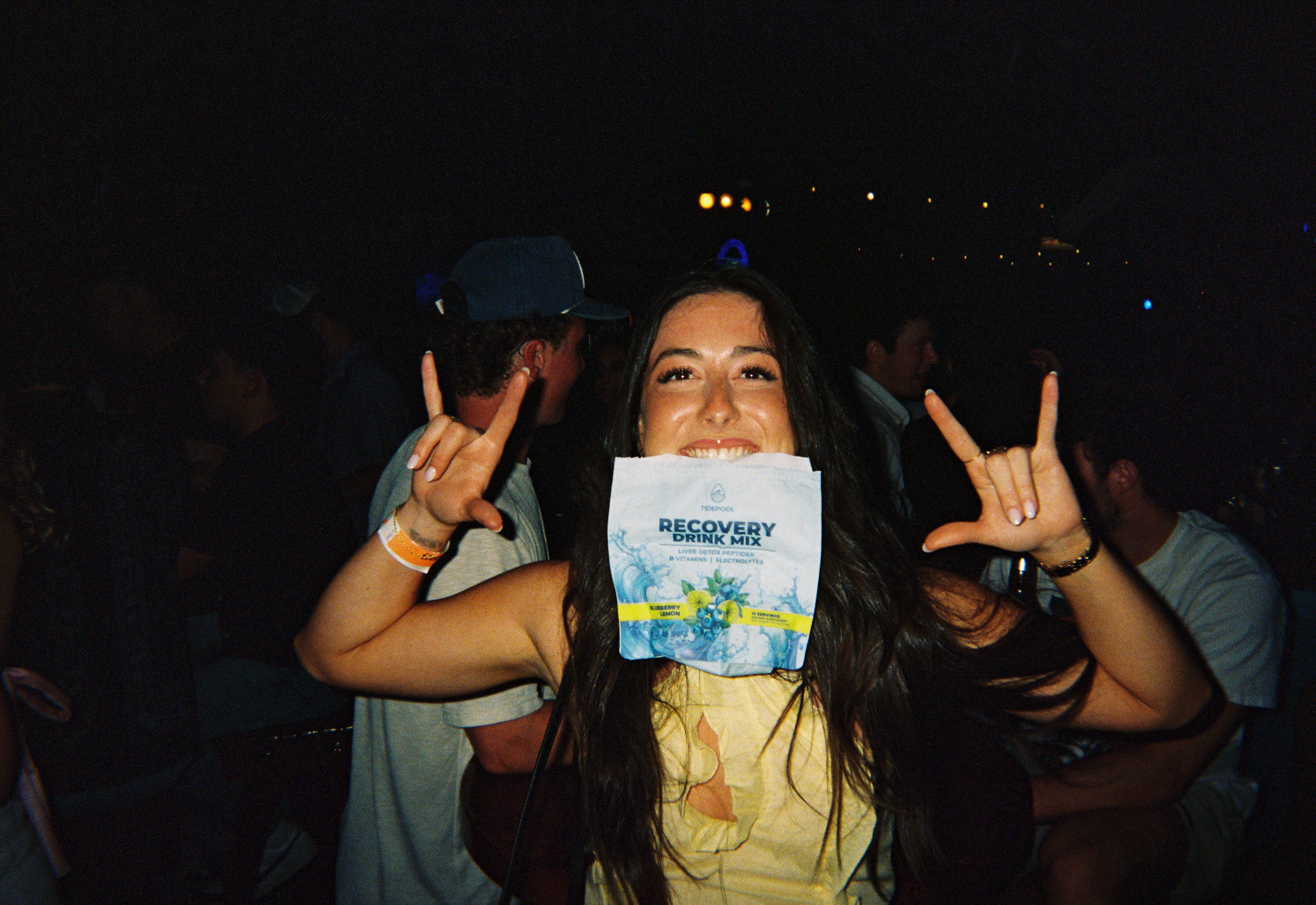 my sister holding tidepool in her mouth and rock star signs at a bar